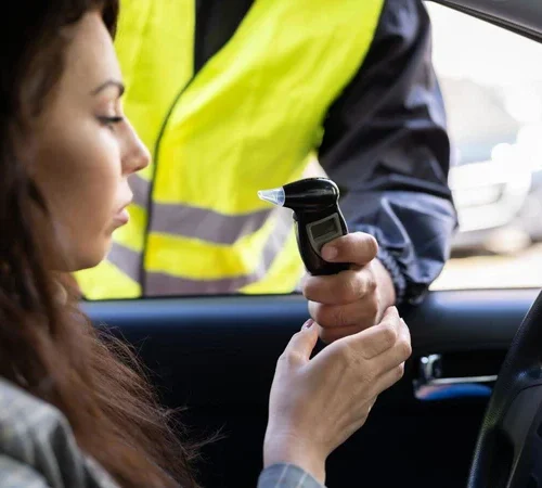 a woman in her car being issued a breathalyzer at a dui stop