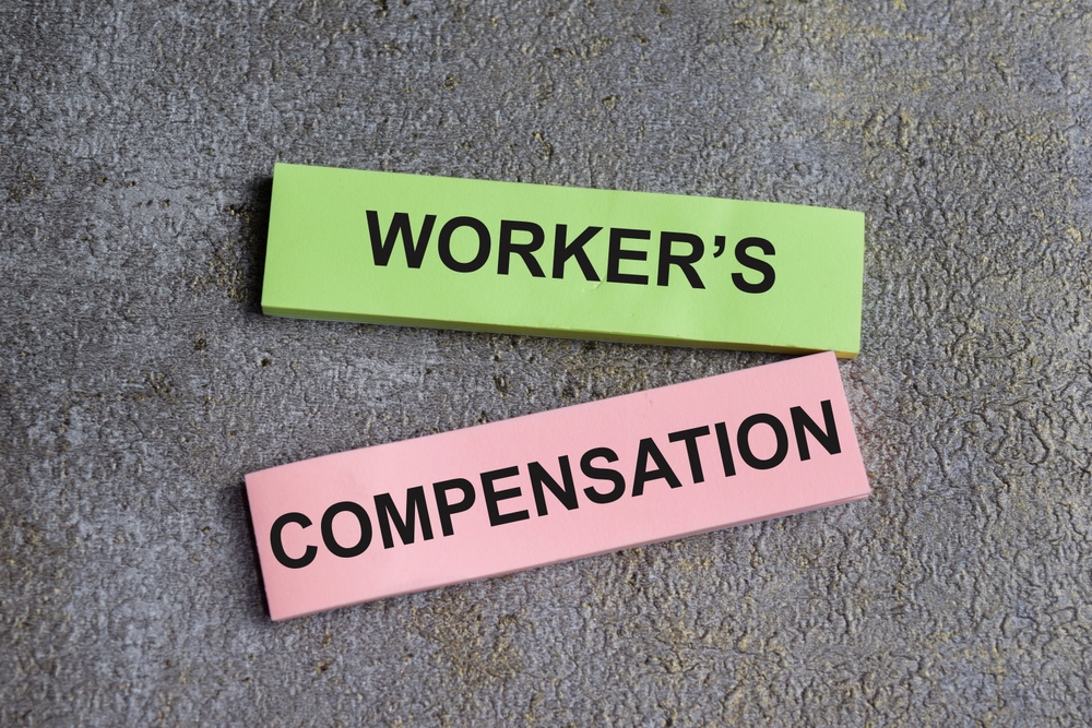 Concept of worker's compensation write on sticky notes isolated on Wooden Table.